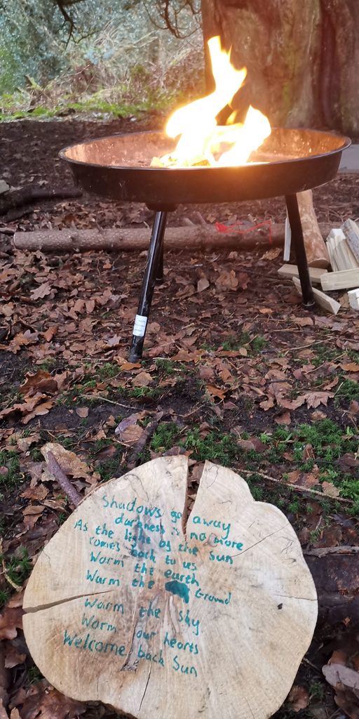 Outdoor fire in the woods with message written on a block of wood