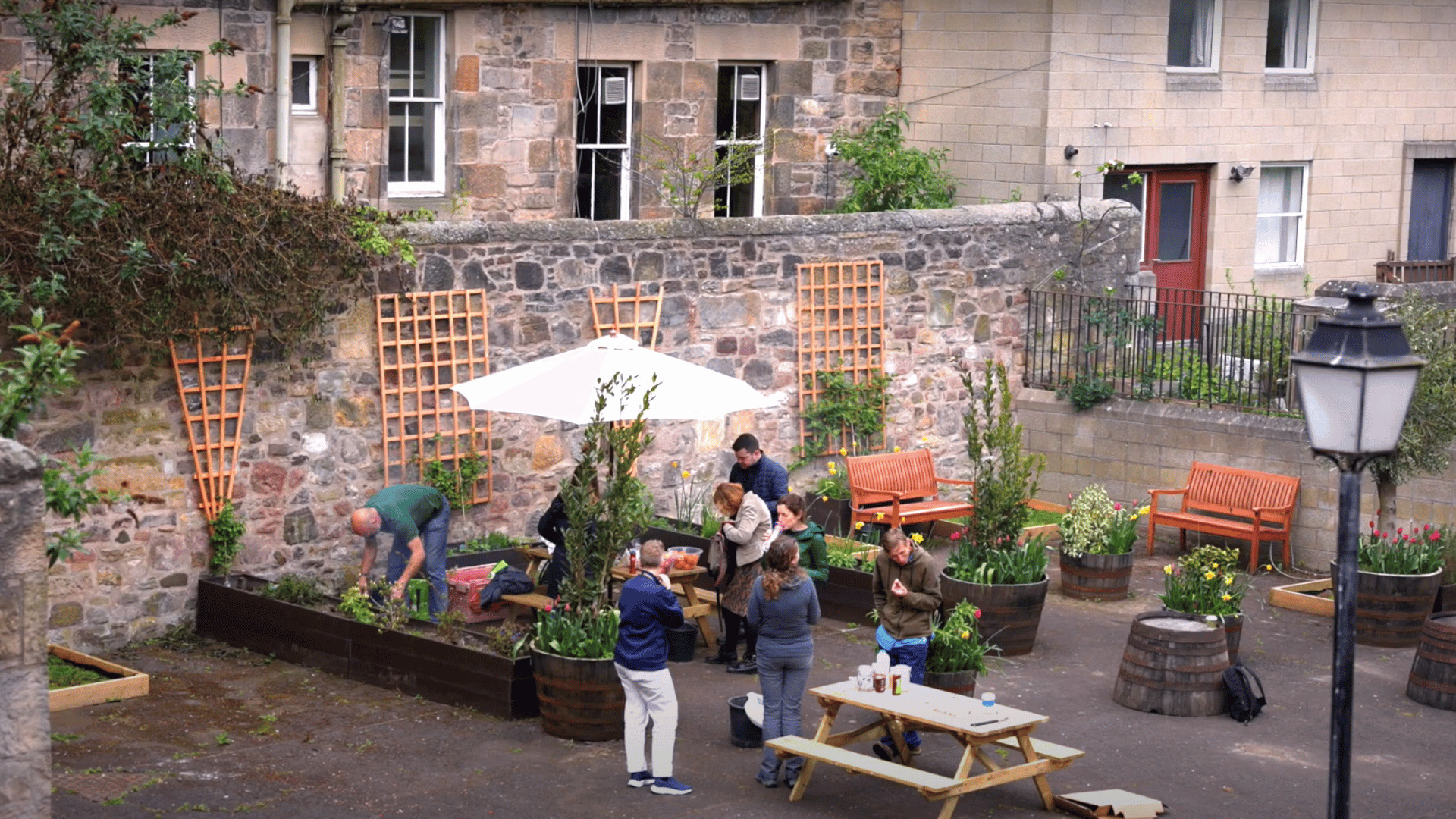 People stood in the Access Place garden. Around the garden are planters with flowers and benches.