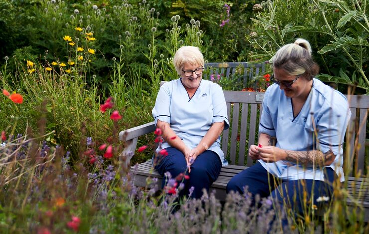 NHS Lothian staff sitting on a bench laughing at Belhaven Hospital Community Garden
