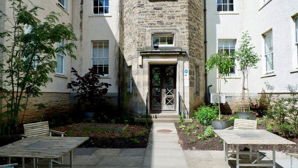 Woodland House Courtyard showing benches and tables as well as plants and trees