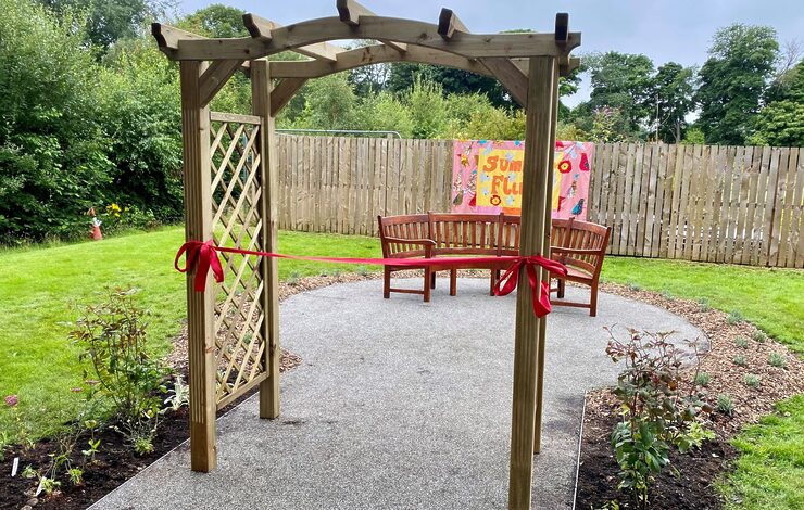 Photo of the new accessible path at the Royal Edinburgh Hospital. You can see a red ribbon ready to be cut to open the path in the foreground and a bench and flowers in the background.