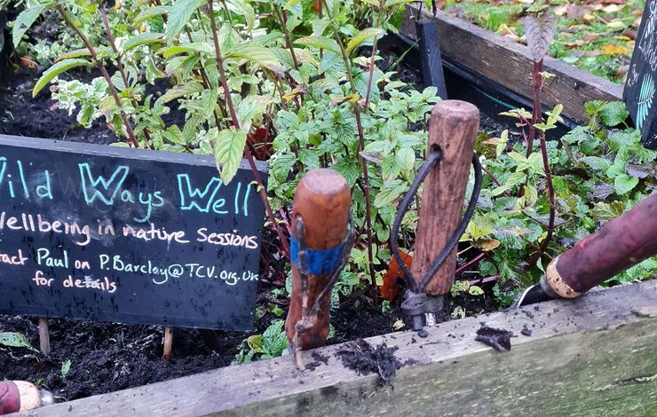 Wild Ways Well sign in a garden with tools