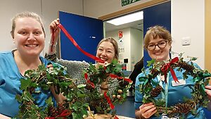 three members of NHS Lothian staff presenting their festive garlands to the camera