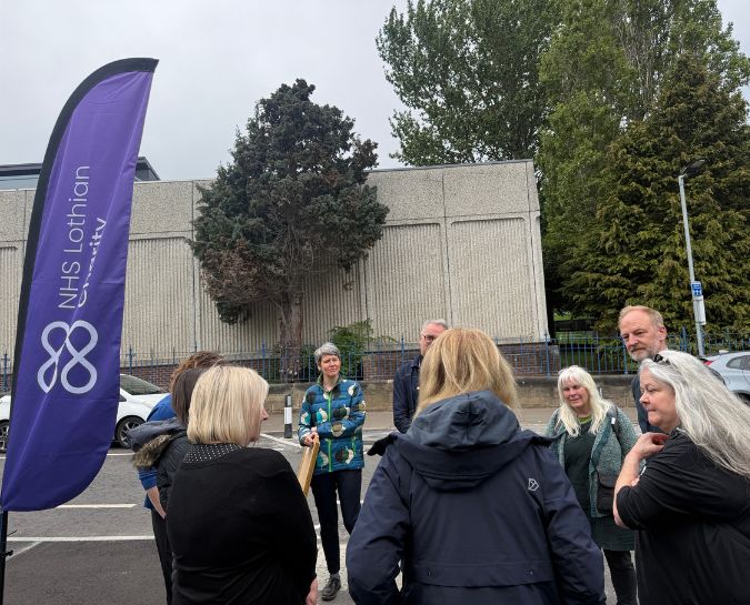 People talking outside next to charity logo